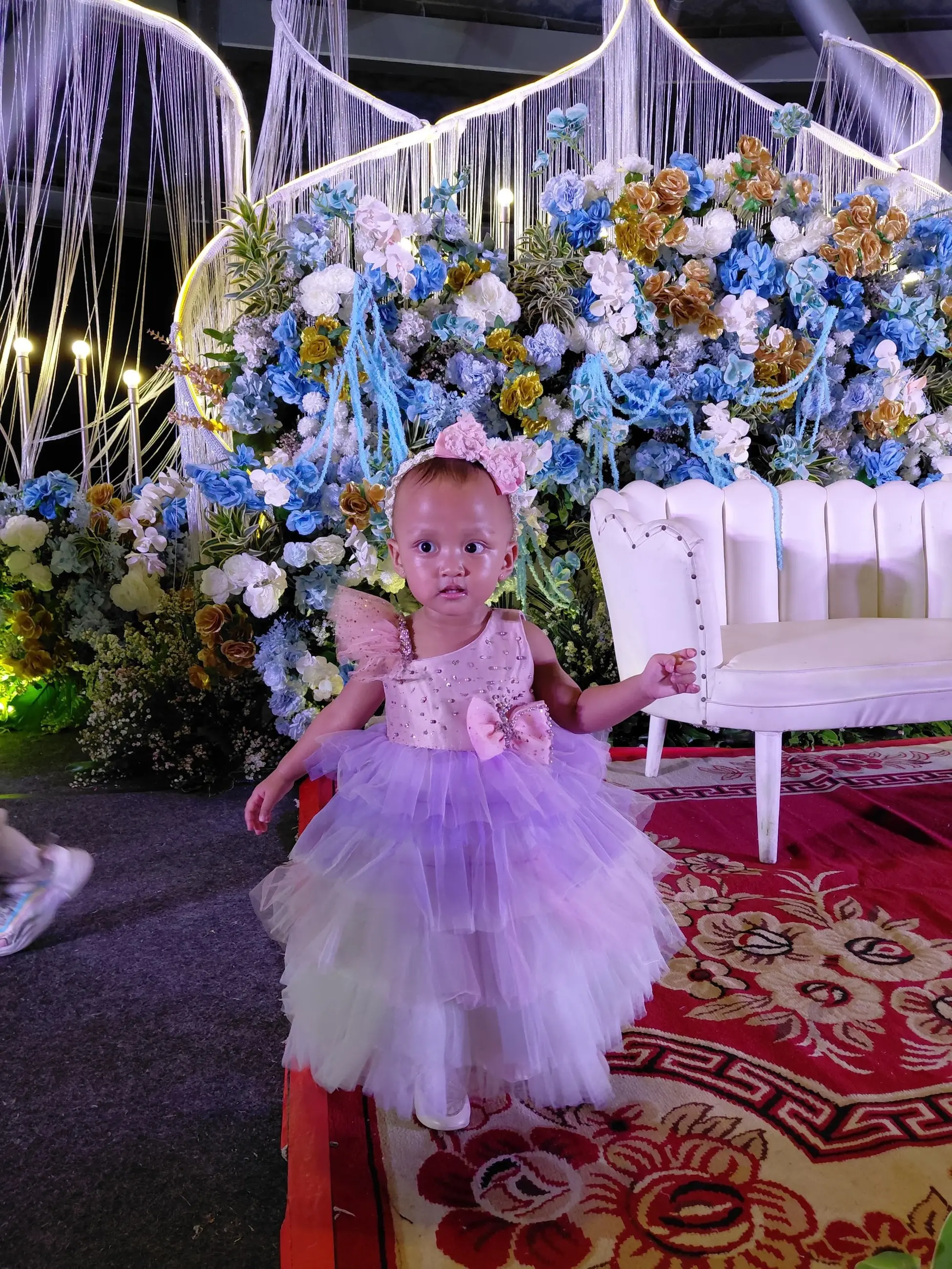 Balita dengan gaun tutu lilac di dekorasi bunga biru