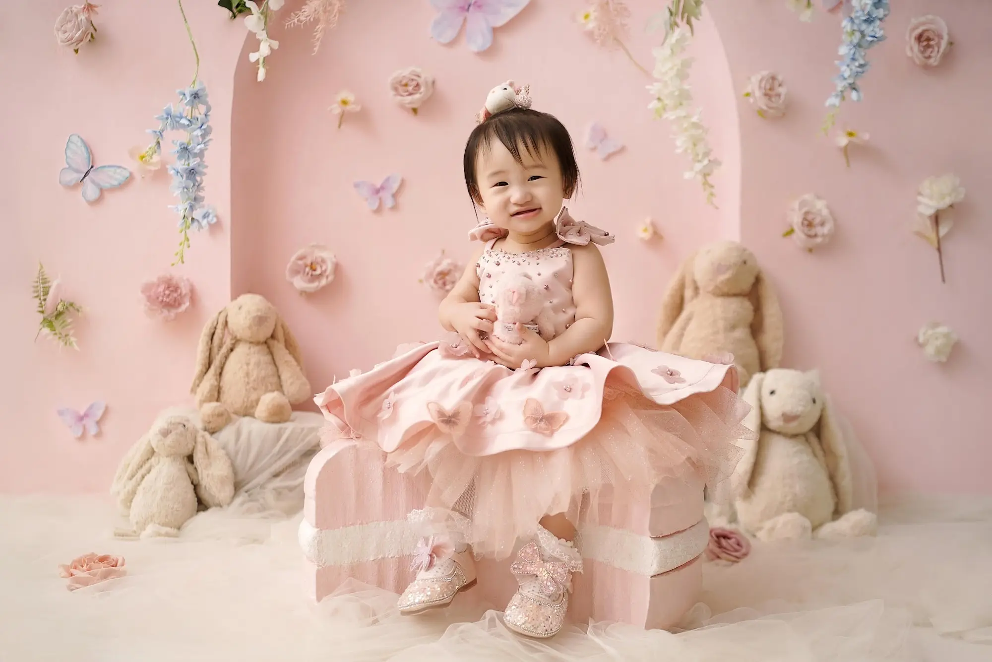 Bayi dengan gaun pink di studio bernuansa pastel