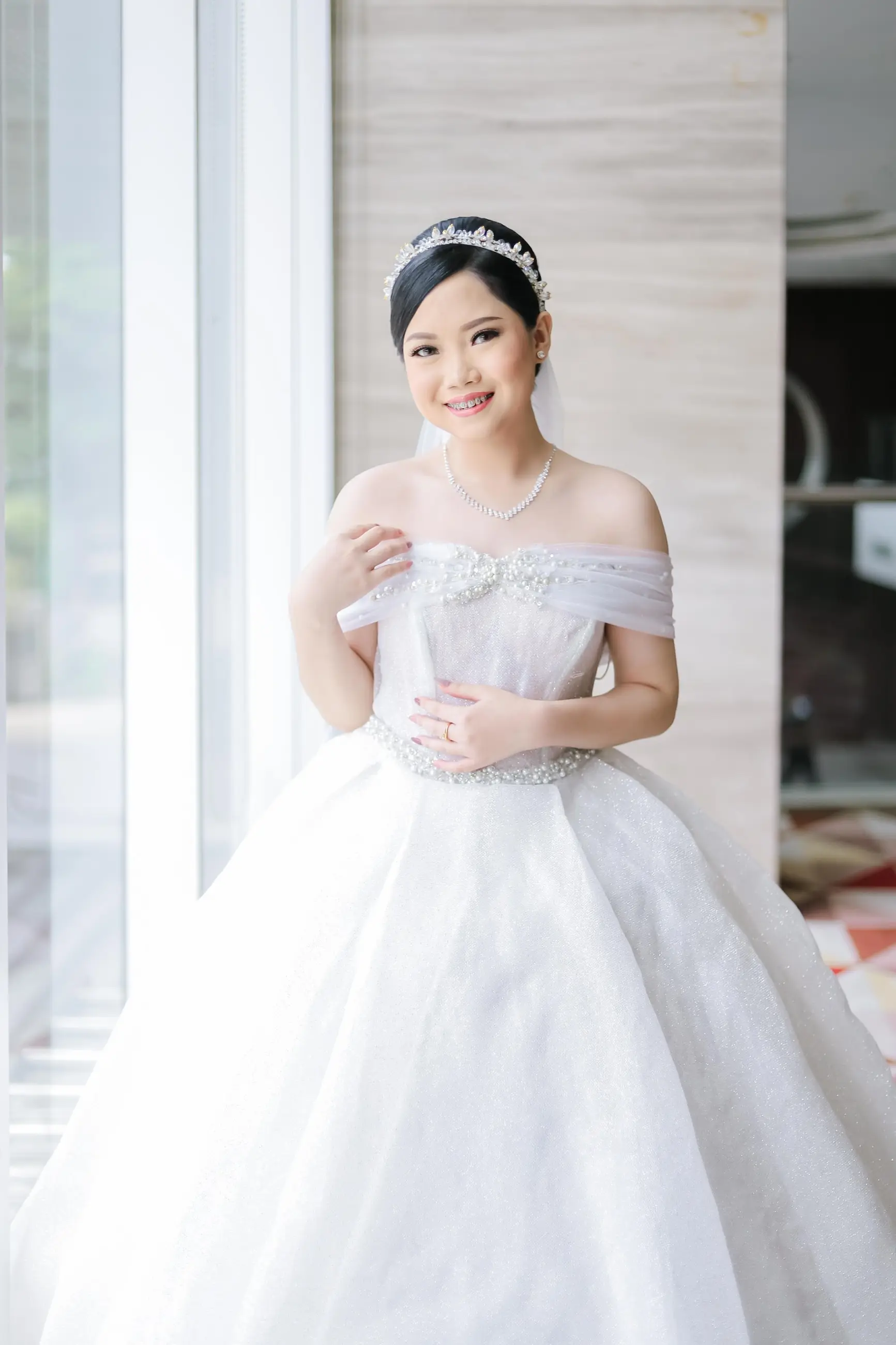 Gaun pengantin ballgown model sabrina di dekat jendela