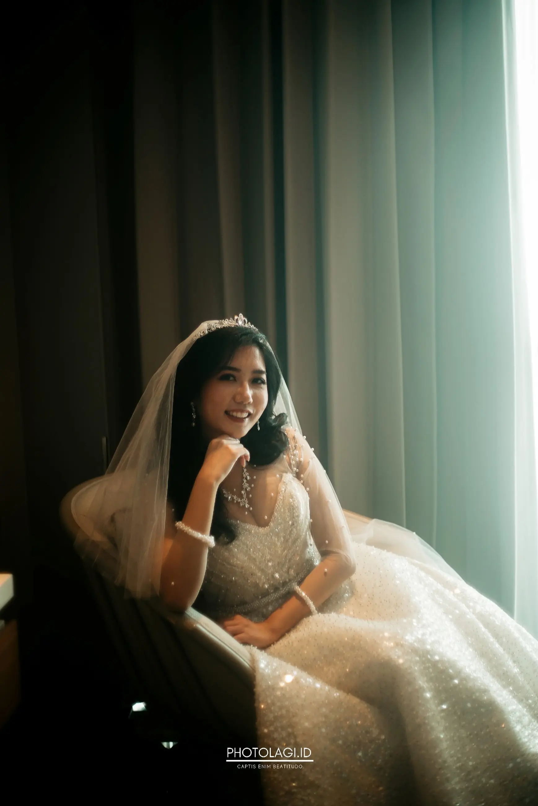 Pengantin HG Bridal duduk di dekat jendela dengan gaun ballgown berpayet dan veil
