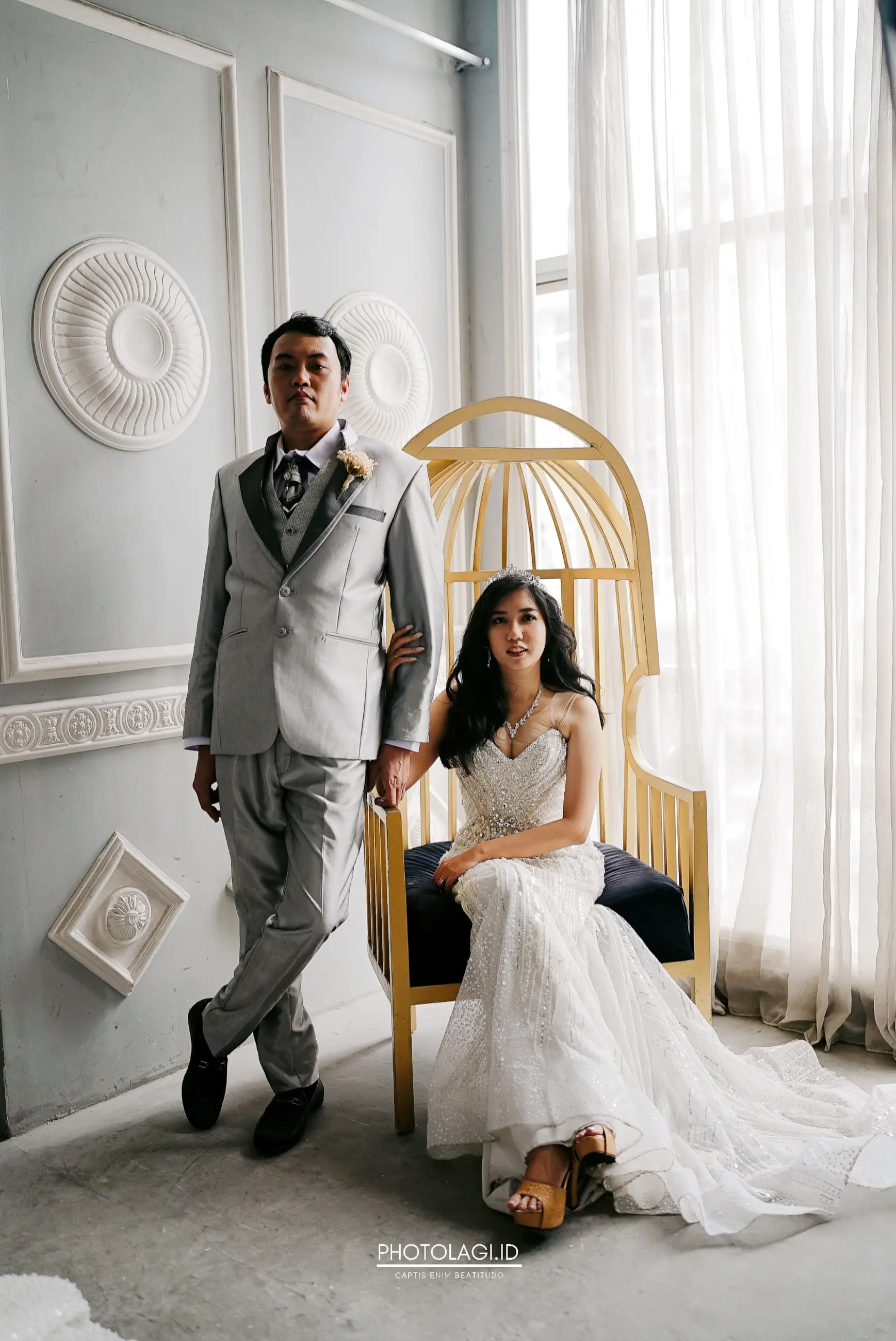 Pengantin pria berjas abu berdiri di samping pengantin wanita