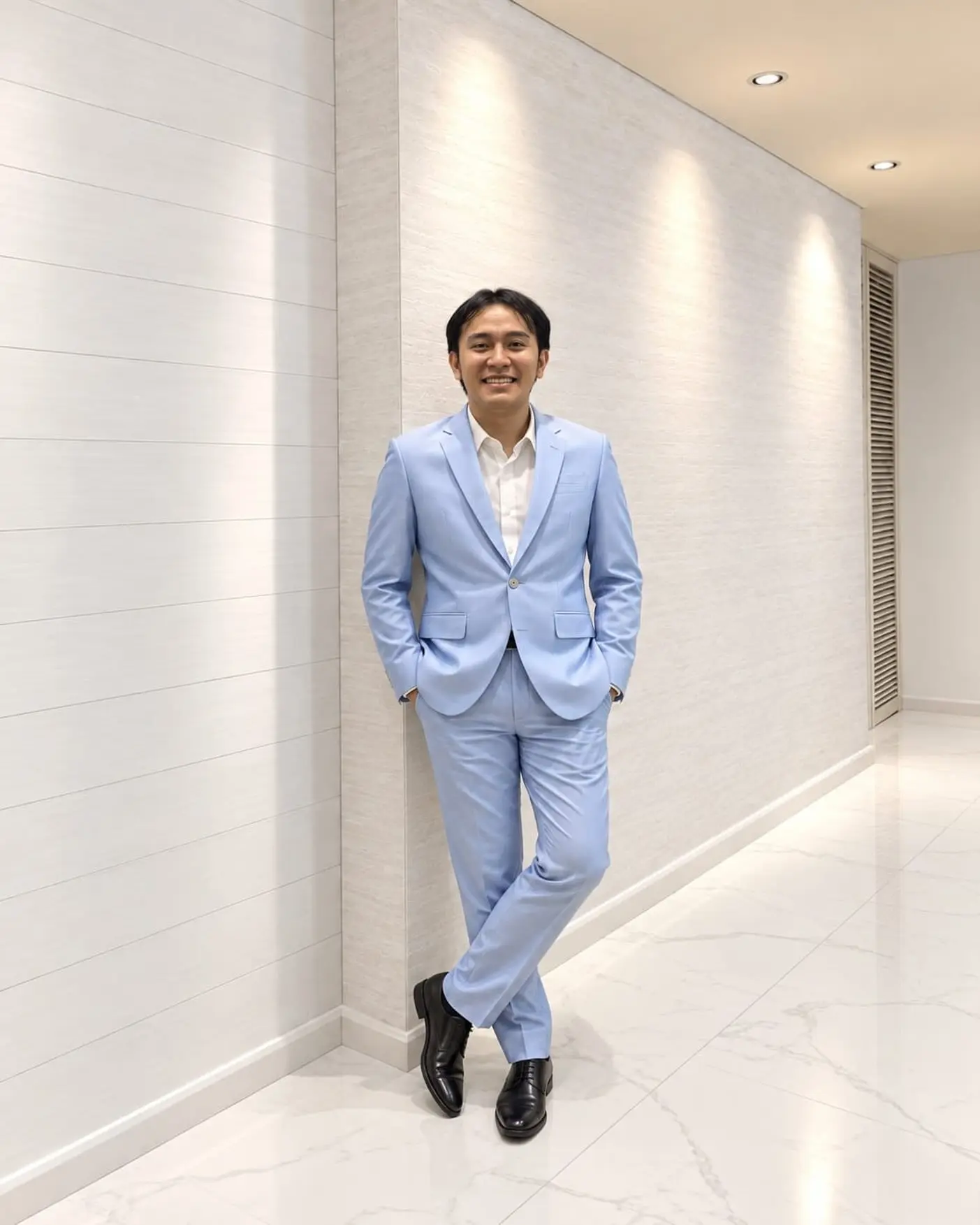 Pria memakai setelan jas biru muda Mr. C Tailor di lorong putih