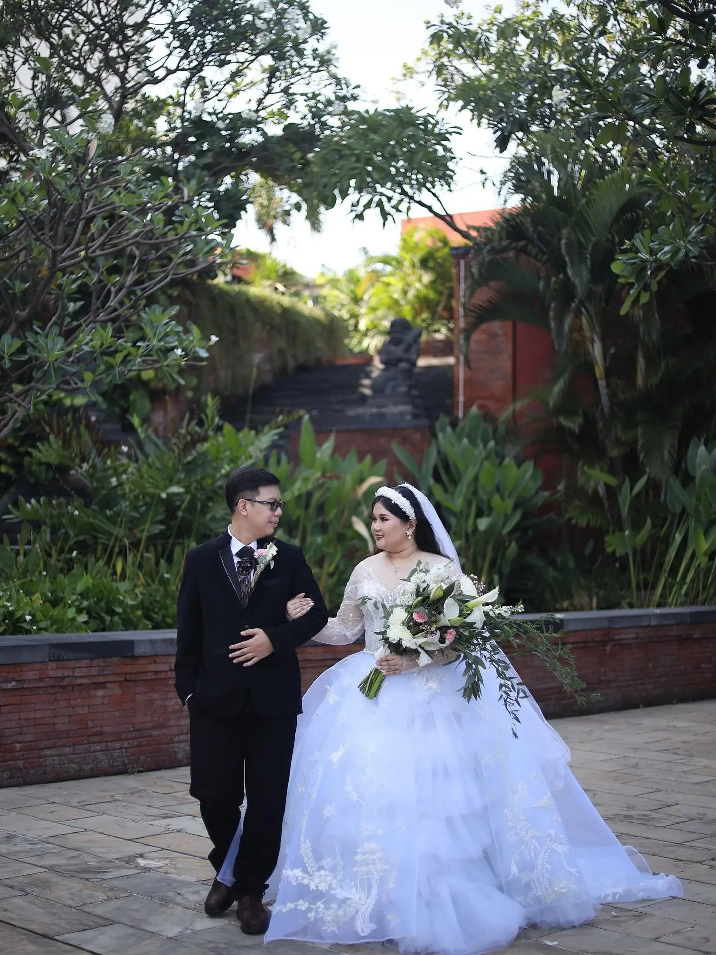 Pengantin pria berjas hitam menggandeng pengantin wanita