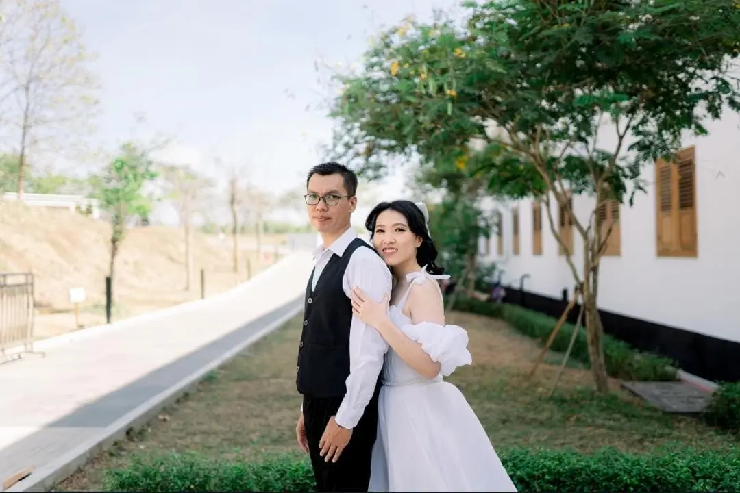 Pasangan berpelukan di taman dengan gaun off-shoulder