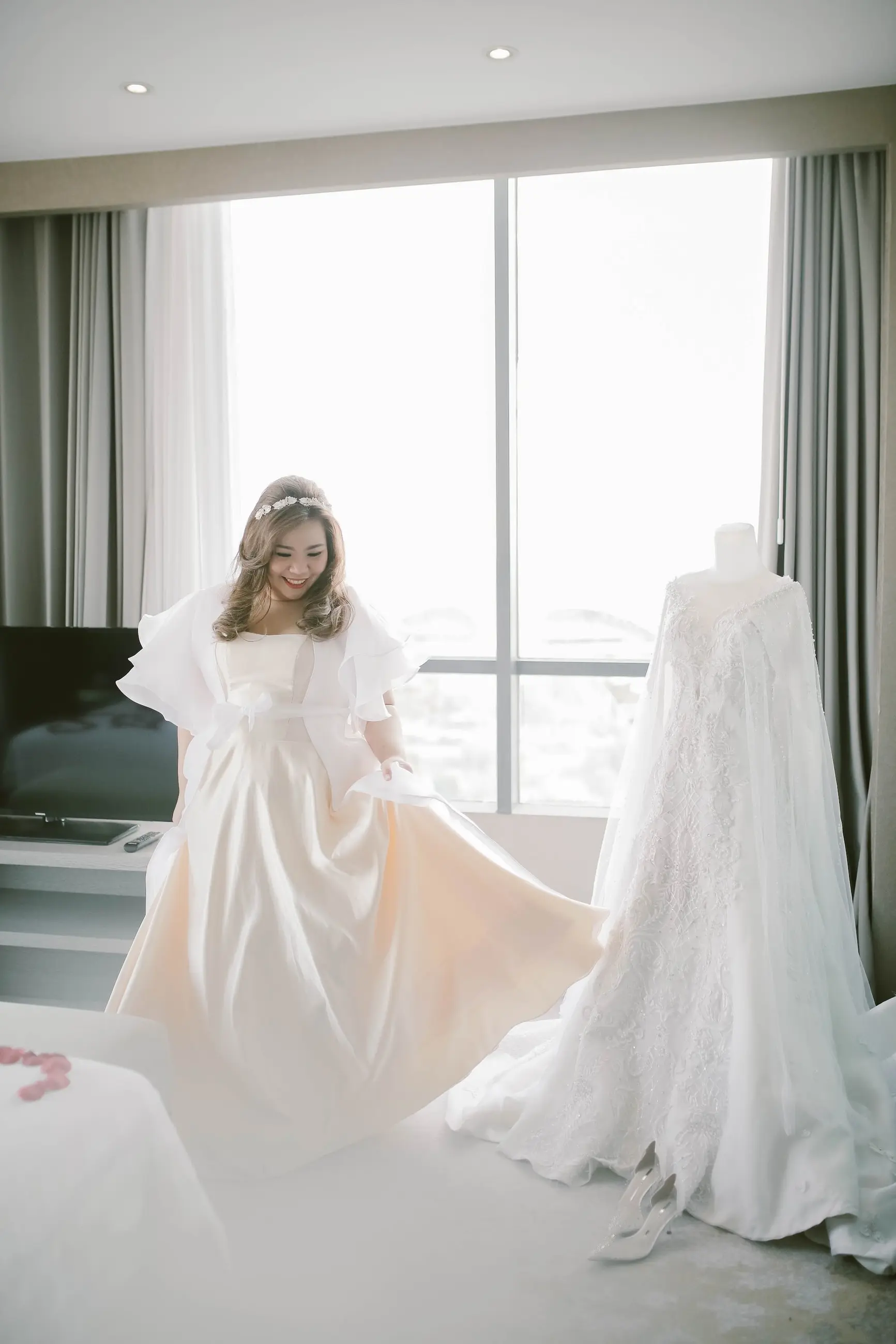Pengantin memakai robe di samping gaun yang dipajang di manekin