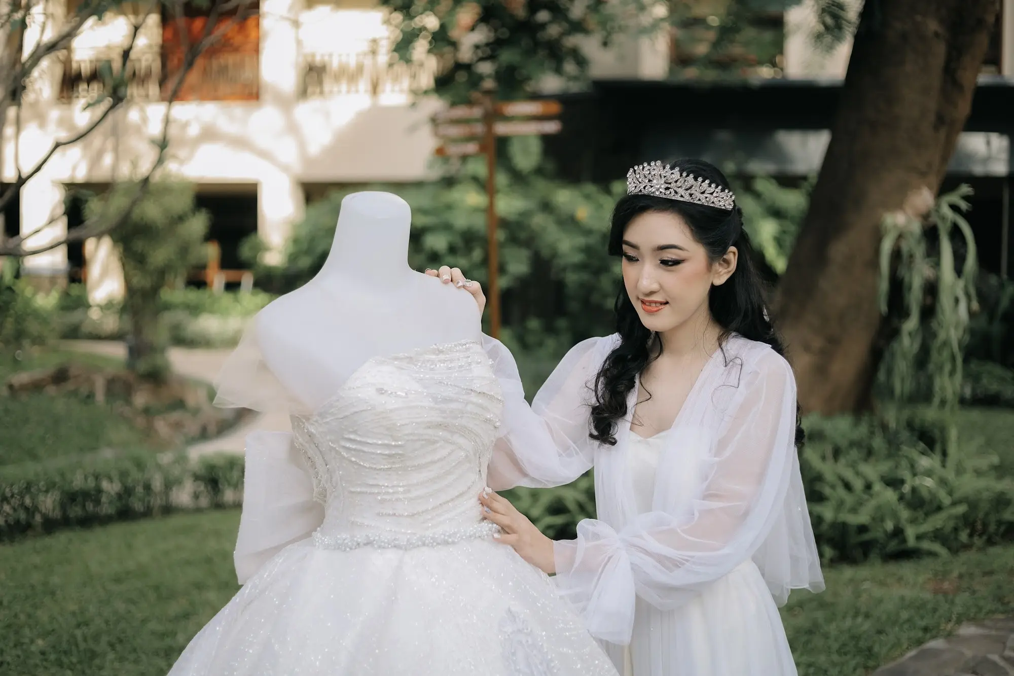 Pengantin merapikan gaun di manekin di taman