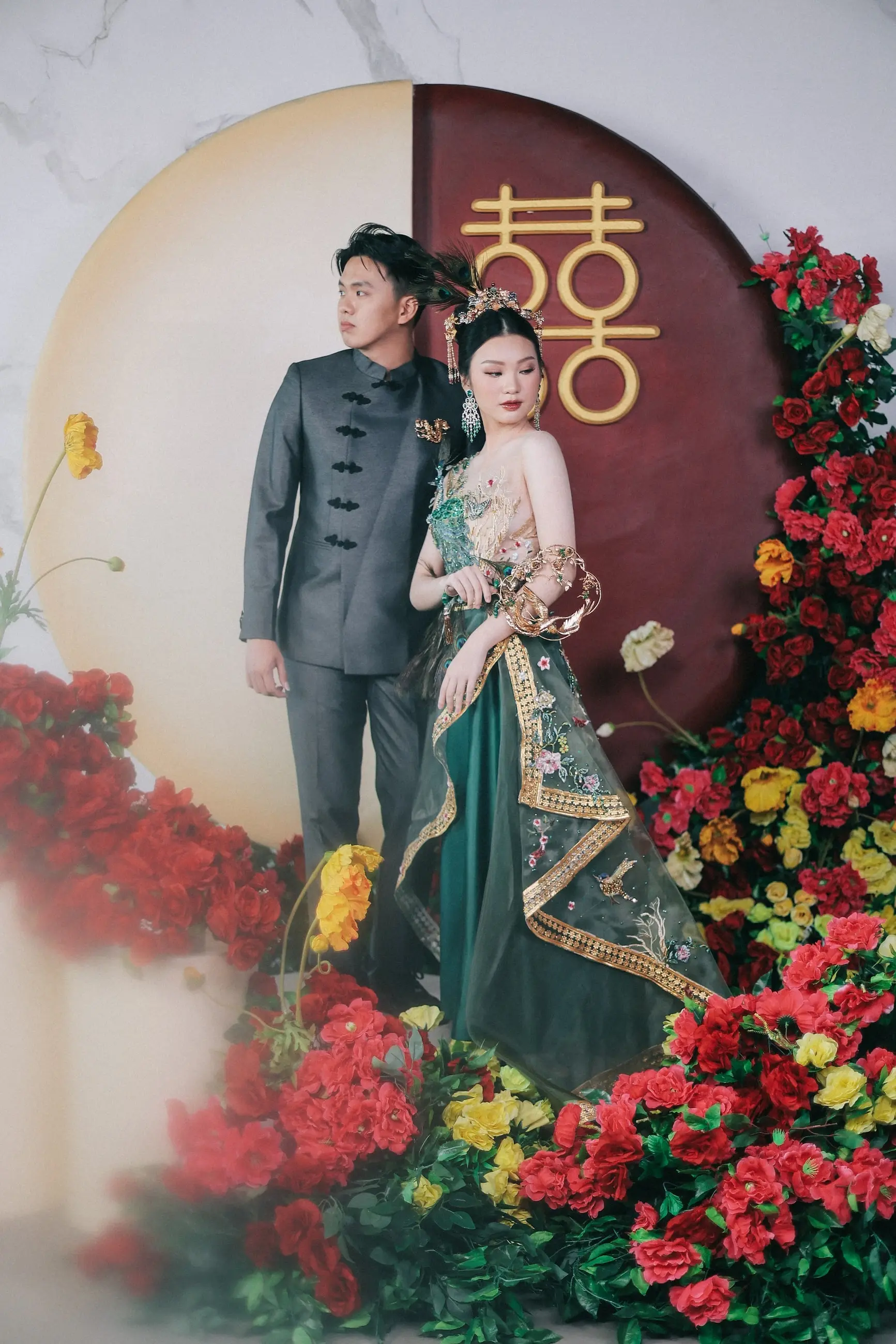 Pasangan sangjit dengan cheongsam hijau di depan lambang double happiness