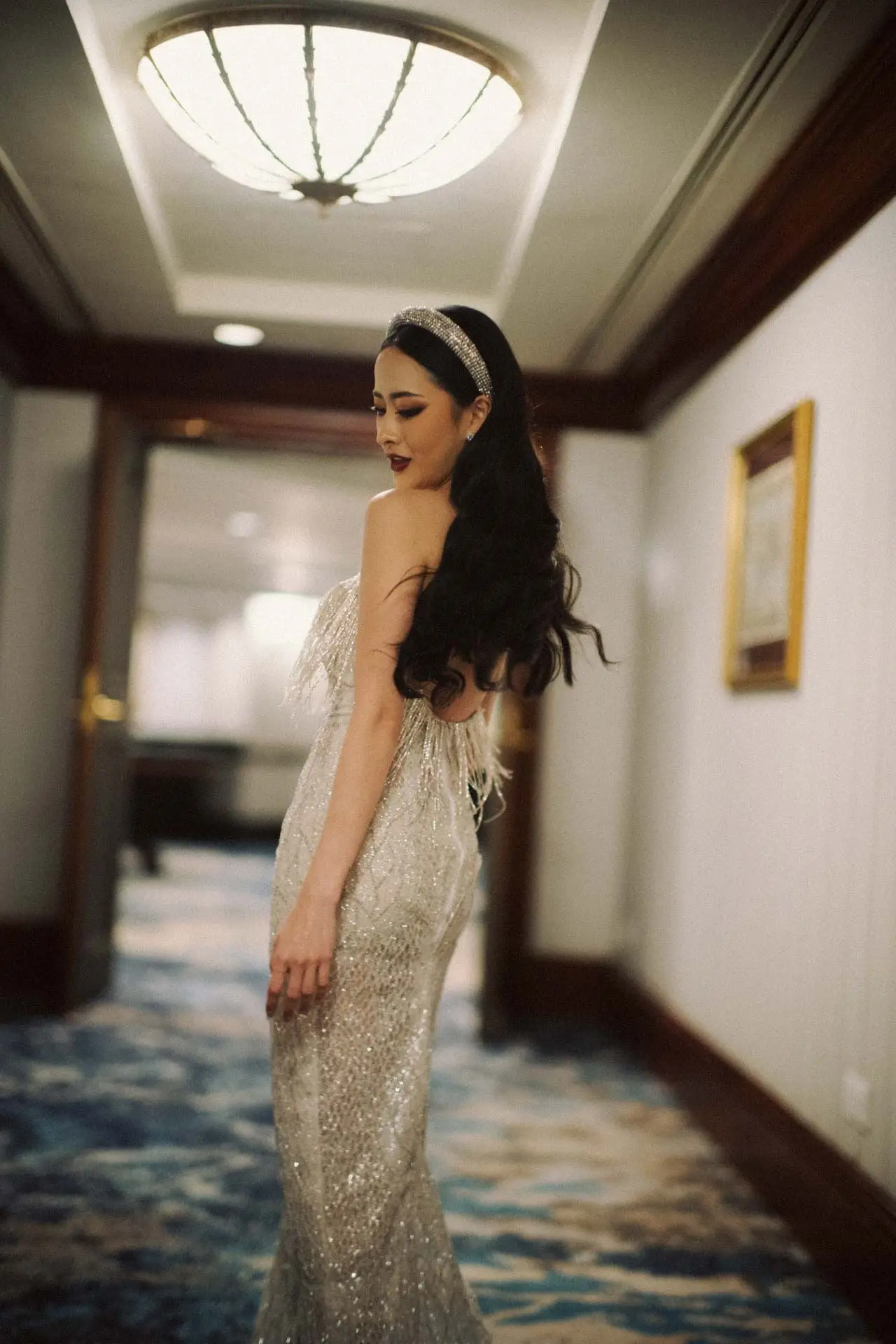 Pengantin dengan gaun mermaid berpayet menoleh di lorong